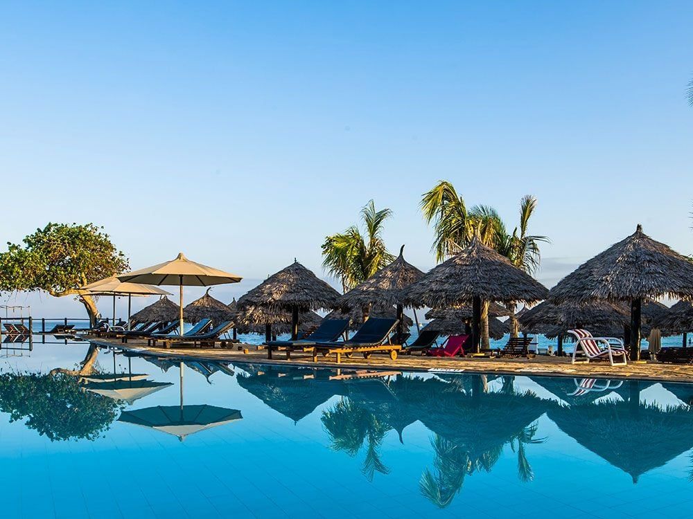 A large swimming pool surrounded by chairs and umbrellas at a resort.