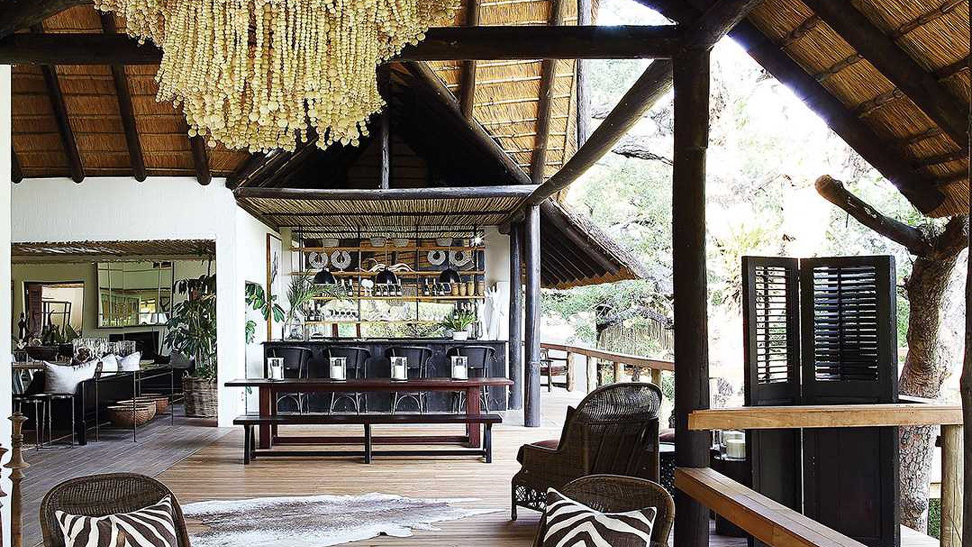 A living room with a thatched roof and a chandelier hanging from the ceiling