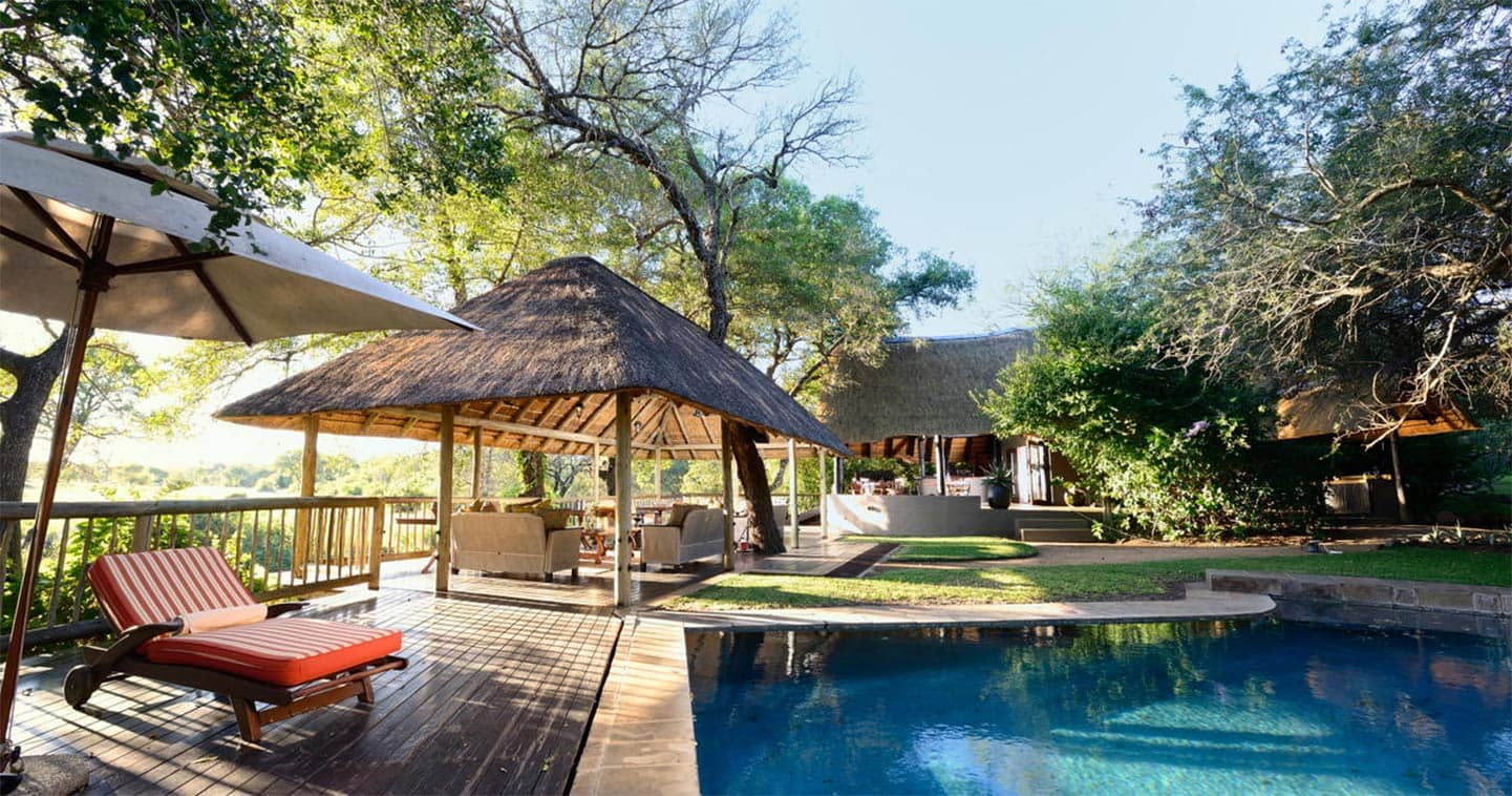 A swimming pool with a thatched hut in the background