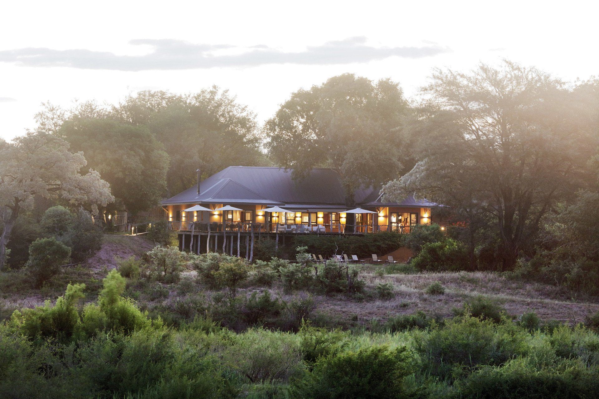 A large house is sitting on top of a hill in the middle of a forest.