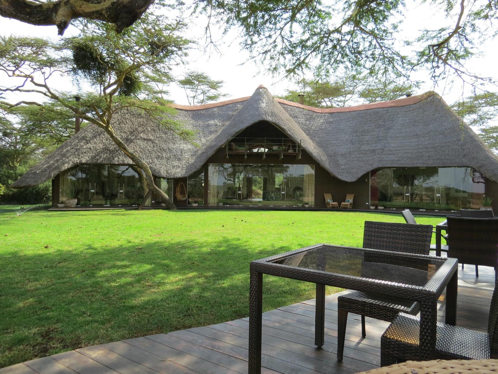 A large house with a thatched roof and a table and chairs in front of it.