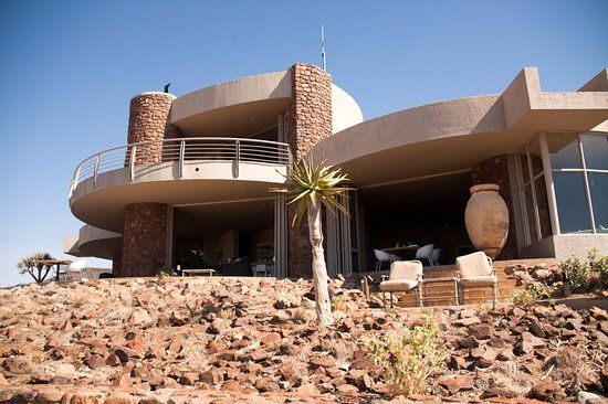 A large house is sitting on top of a rocky hill.