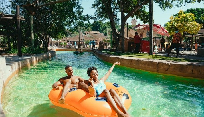 A man and a woman are floating on an orange raft in a pool.