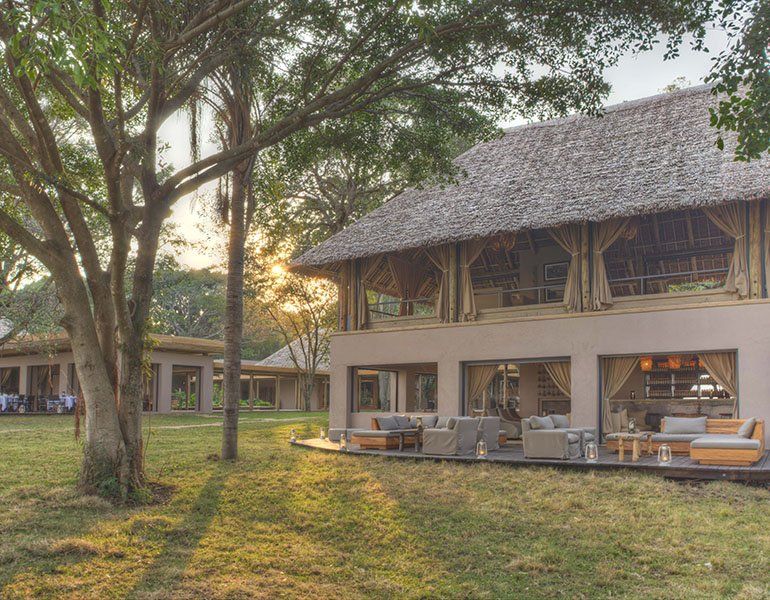 A large house with a thatched roof is surrounded by trees and grass.