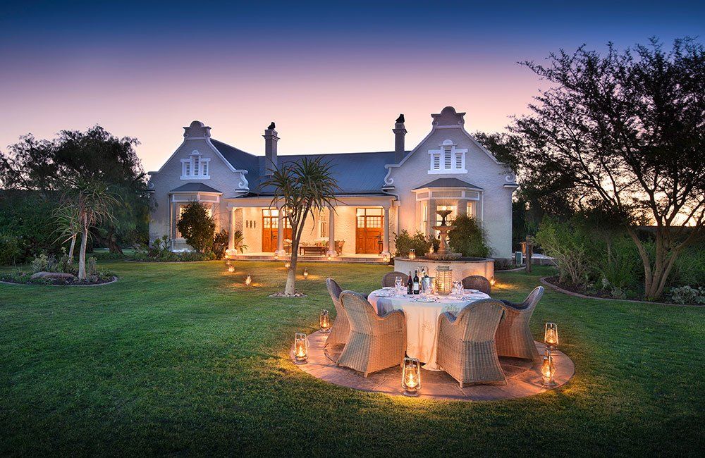 A large white house with a table and chairs in front of it