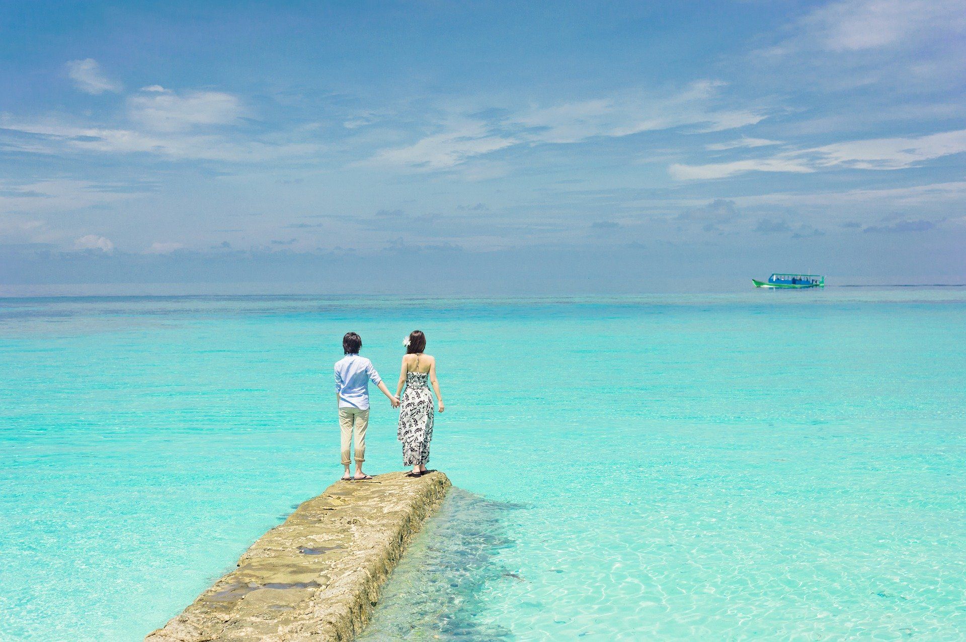 A man and a woman are standing on a pier overlooking the ocean.
