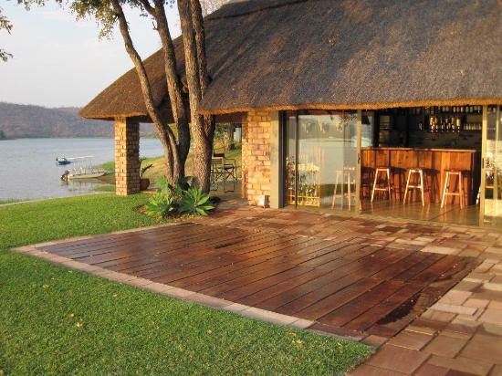 A house with a thatched roof sits next to a body of water