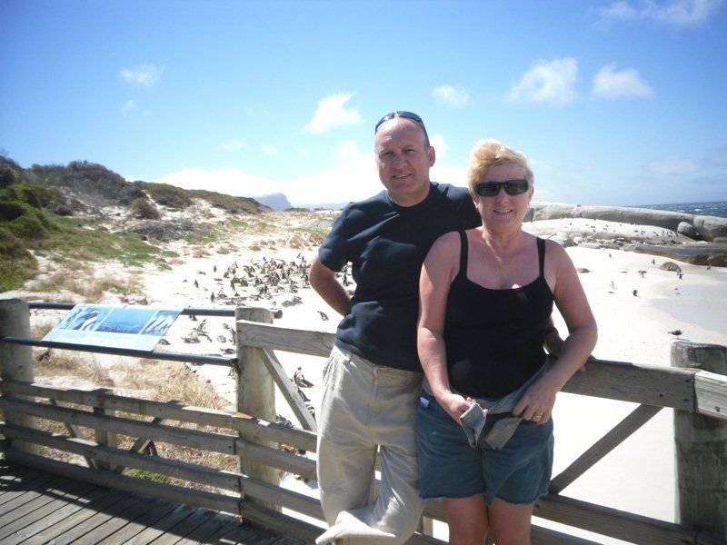 A man and a woman are posing for a picture in front of a beach