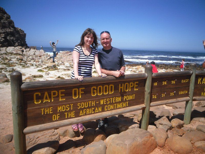 A man and a woman standing in front of a sign that says cape of good hope