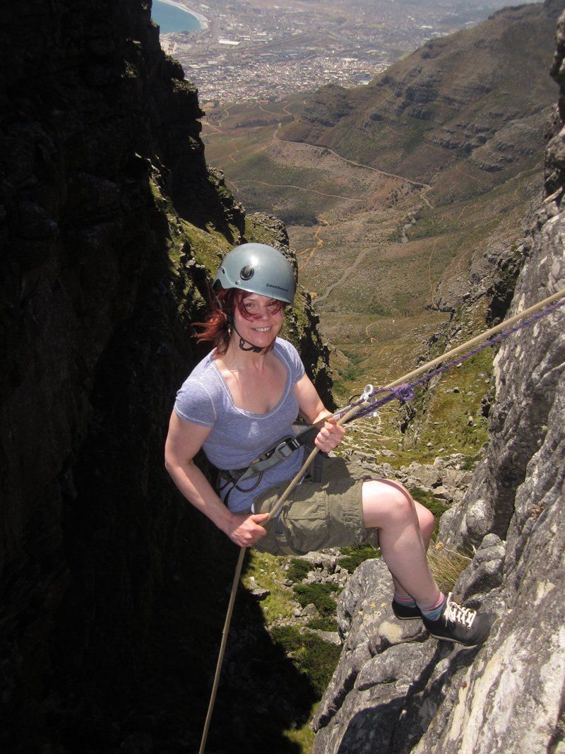 A woman wearing a helmet is climbing a mountain.