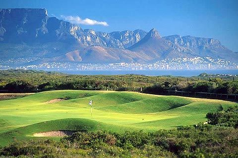 A golf course with mountains in the background and a city in the distance