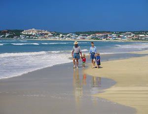 A family is walking on the beach near the ocean.