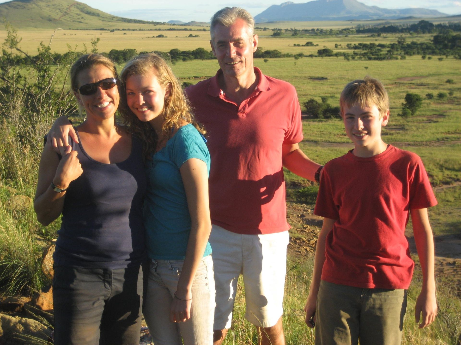 A family posing for a picture in a field with mountains in the background