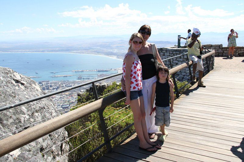 A group of people standing on a wooden deck overlooking a body of water