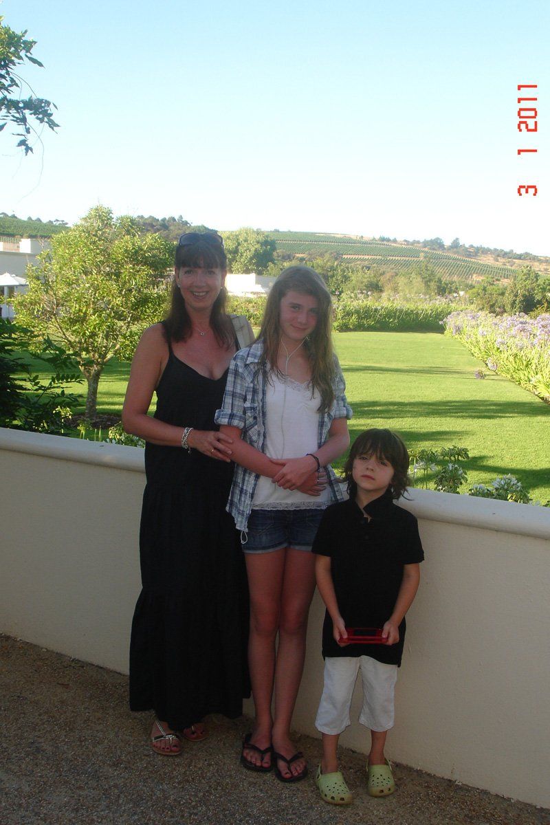 A woman and two children are standing next to each other in front of a wall ..
