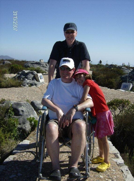 A man in a wheelchair is posing for a picture with two other people
