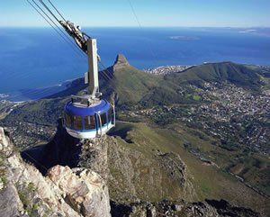 A cable car is going up a mountain overlooking the ocean