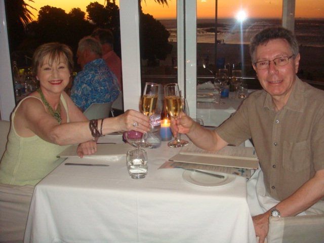 A man and a woman are sitting at a table toasting with champagne glasses