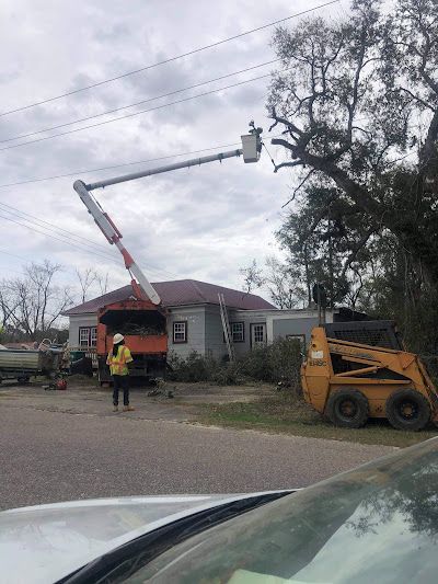 A man is standing next to a crane in front of a house.