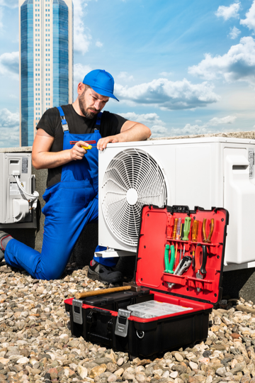 A man is fixing an air conditioner on the roof of a building.