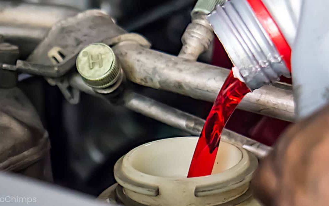 A person is pouring red liquid into a bottle of oil.