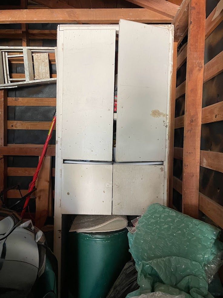 A white cabinet is sitting in a wooden shed.