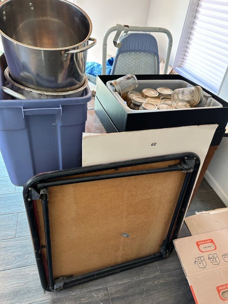 A room filled with boxes , pots and pans and a table.