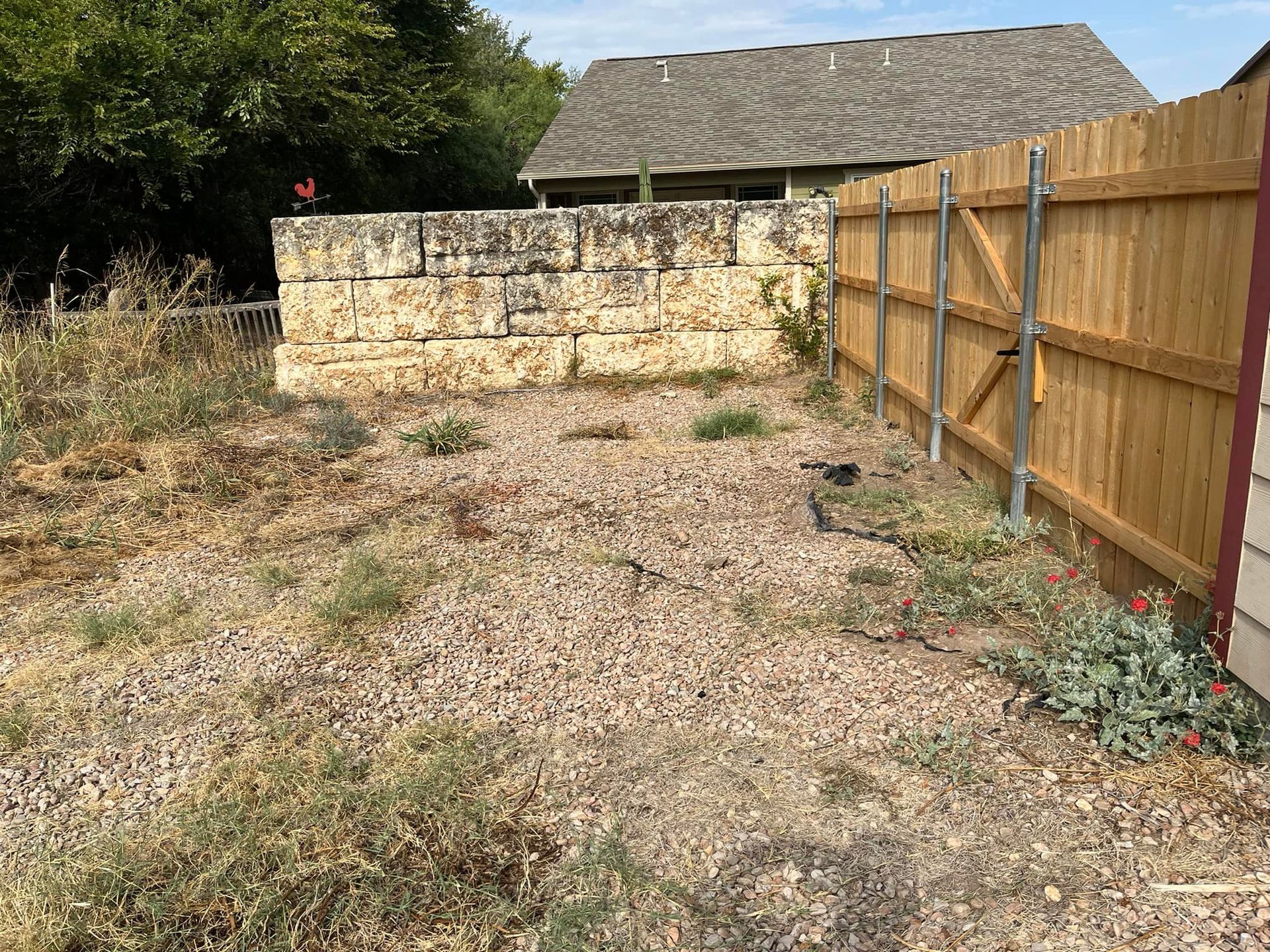 A backyard with a wooden fence and a stone wall.