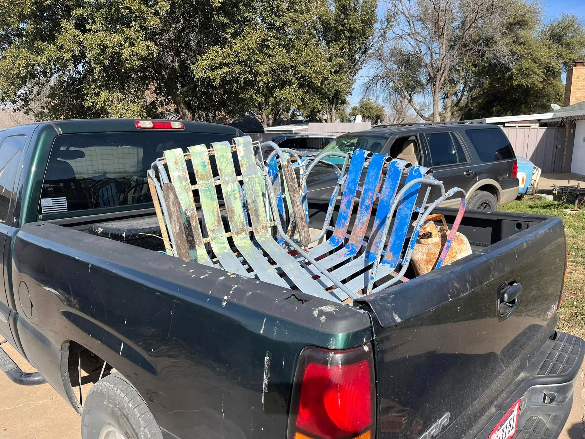 A black truck with a bunch of chairs in the back.