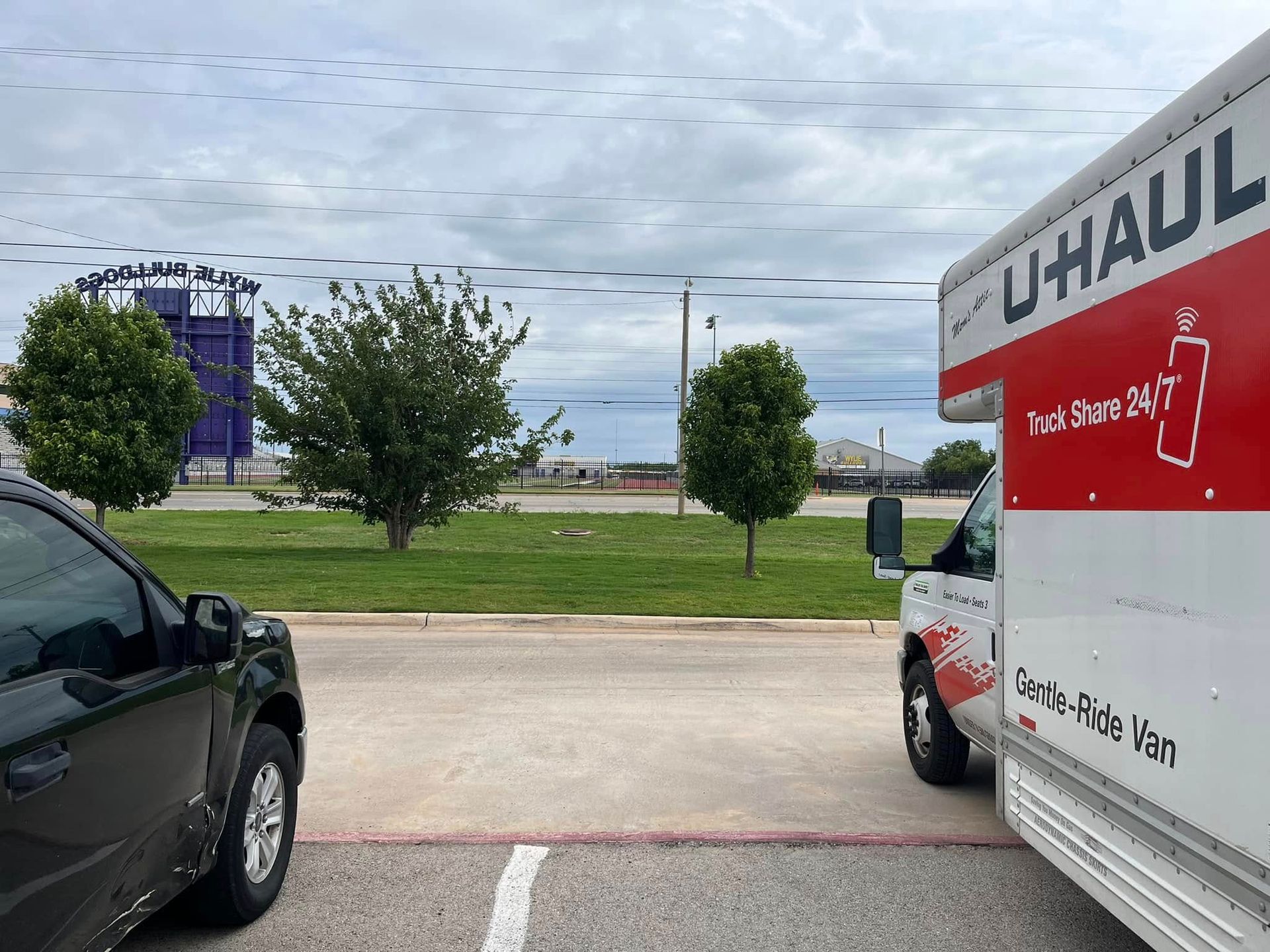 A uhaul truck is parked next to a car in a parking lot