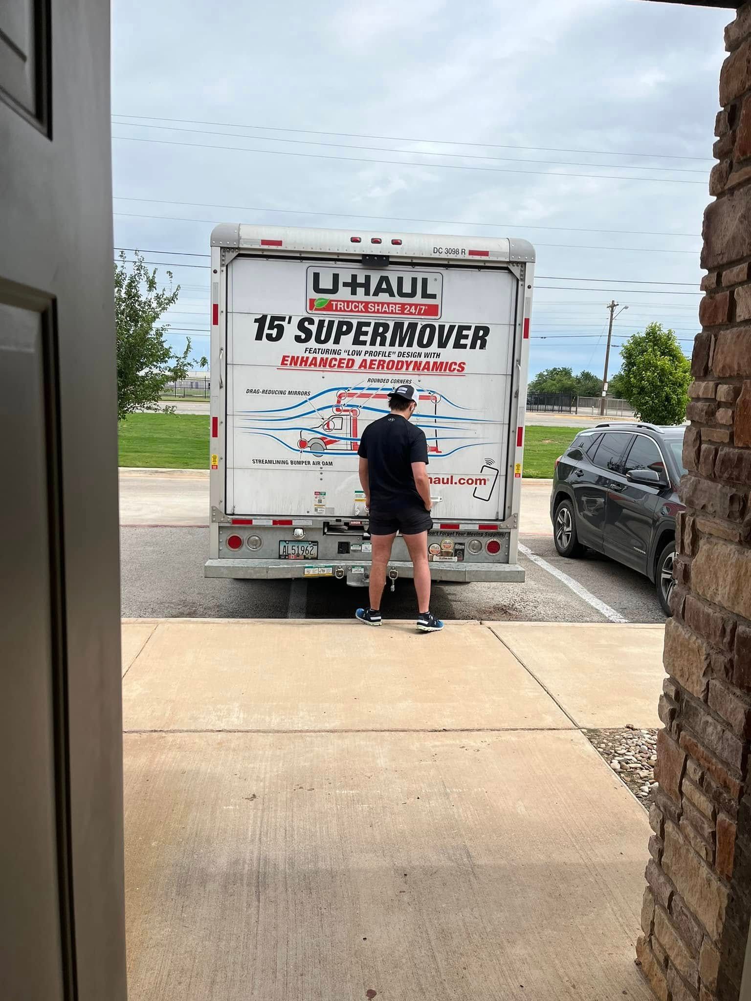 A man is standing in front of a u-haul truck.