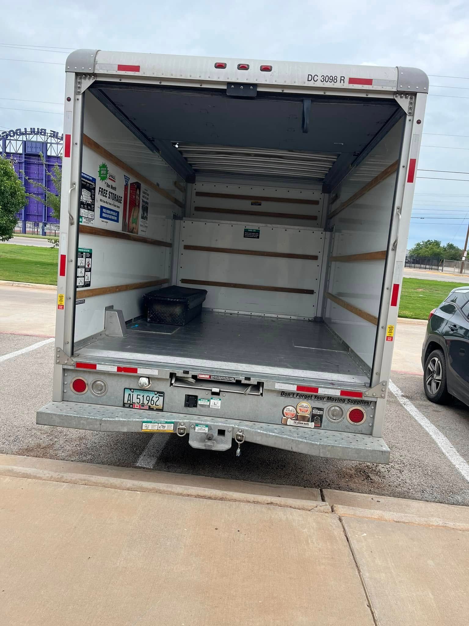 A moving truck is parked in a parking lot with the back door open.