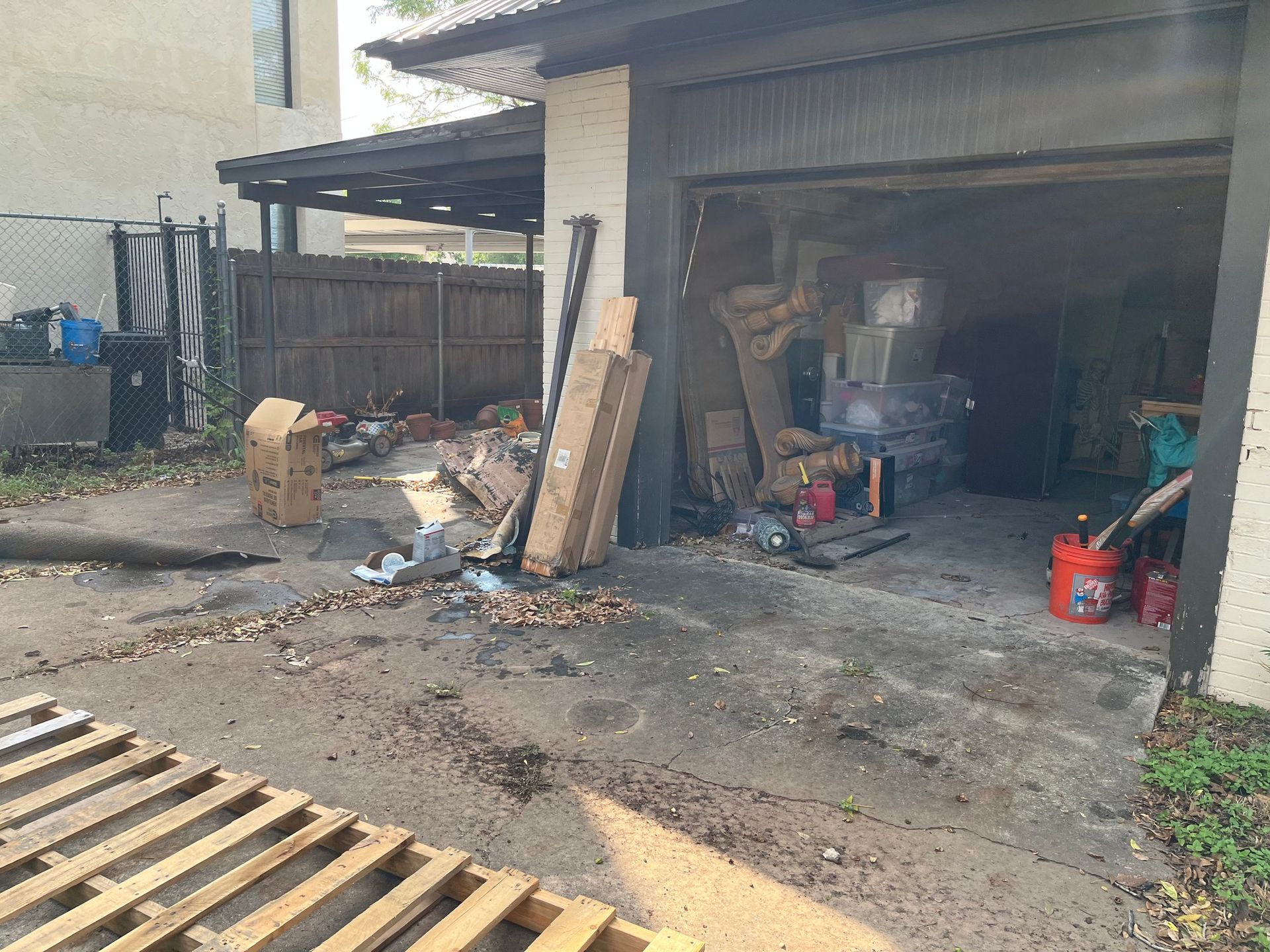 A garage filled with lots of garbage and wooden pallets.