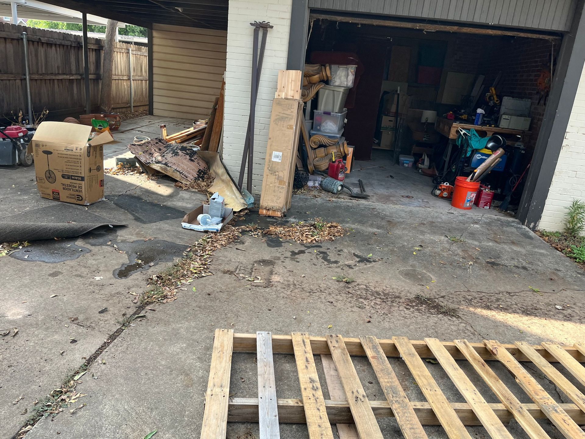 A garage filled with lots of junk and wooden pallets.