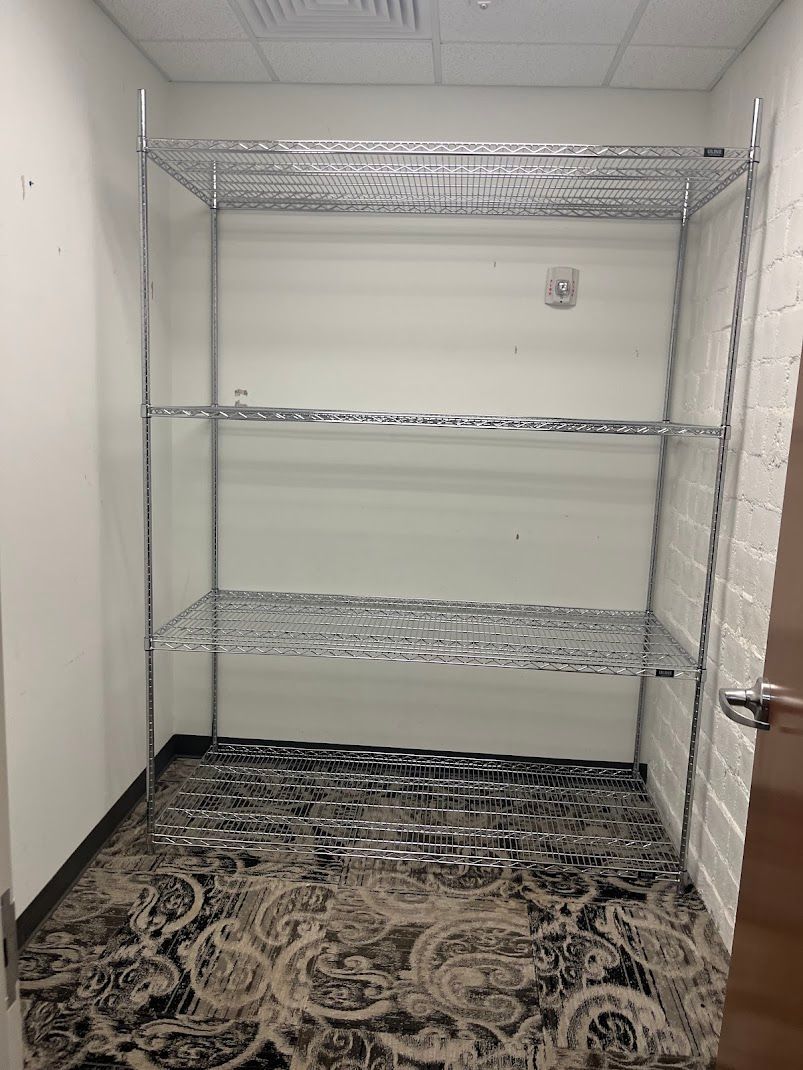 An empty room with a metal rack and a rug on the floor.