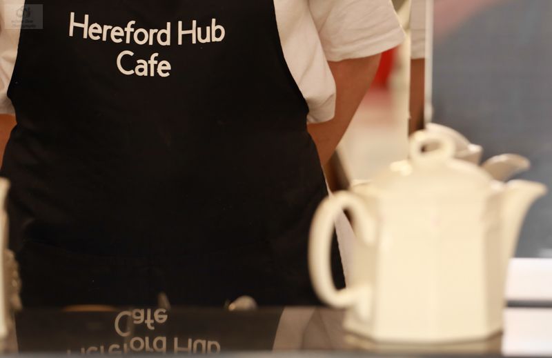 A person wearing an apron that says hereford hub cafe