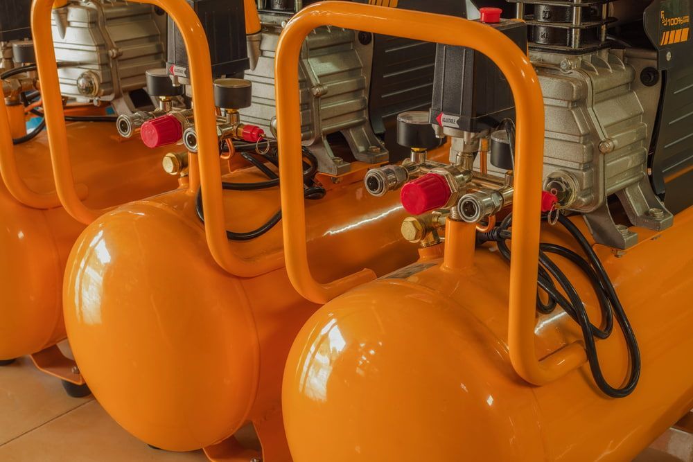 Three Yellow Air Compressors Are Sitting Next To Each Other On A Tiled Floor — Hitemp Compressed Air Services in Kiama, NSW
