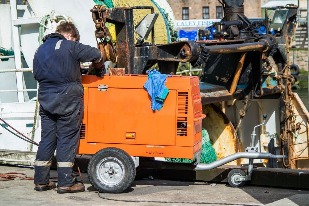 A Man Is Working On A Machine On A Trailer — Hitemp Compressed Air Services in Fairy Meadow, NSW