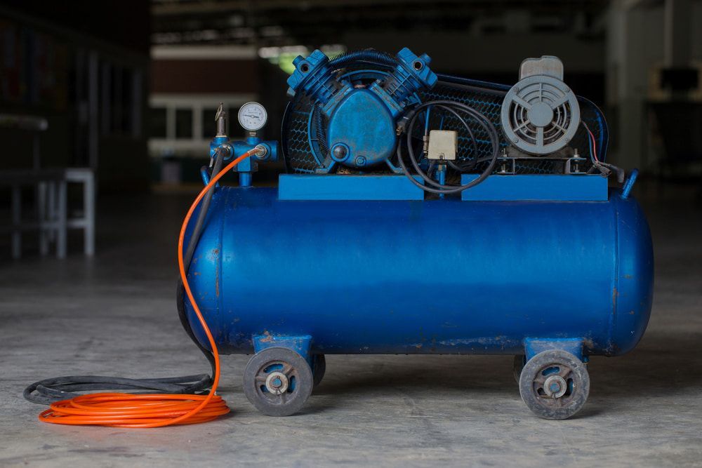 A Blue Air Compressor Is Sitting On The Floor In A Warehouse — Hitemp Compressed Air Services in Campbelltown, NSW