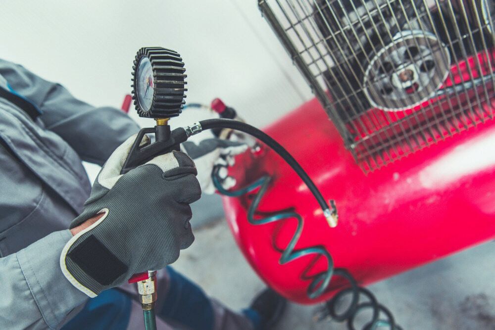 A Man And A Pressure Gauge To Check The Pressure Of An Air Compressor — Hitemp Compressed Air Services in Shellharbour, NSW