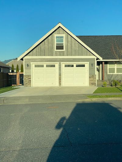 A house with two garage doors and a shadow of a car in front of it.