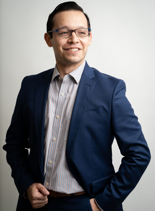 A woman is sitting at a desk with a laptop and a vase of flowers.
