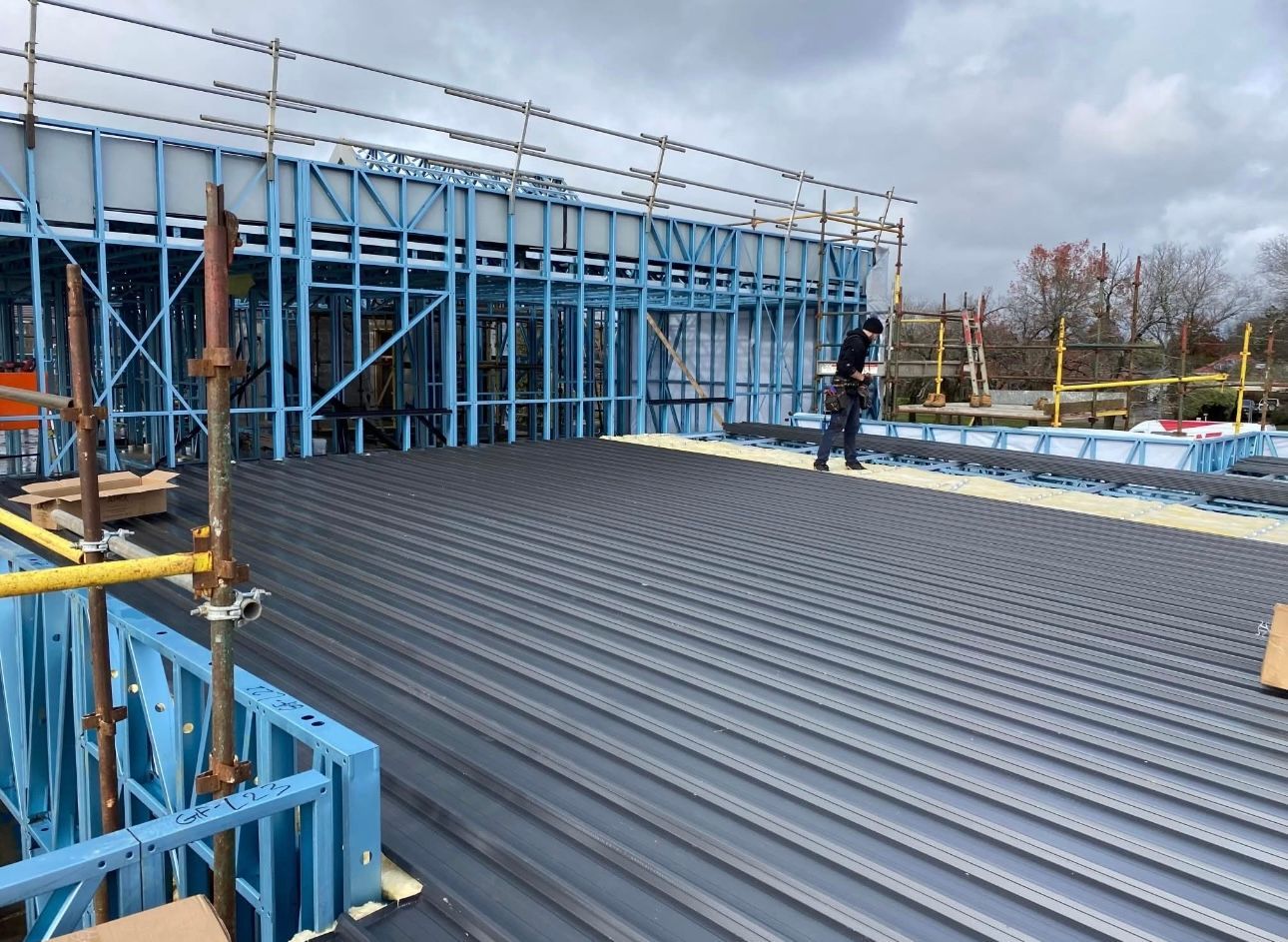 A Man is Standing on the Roof of a Building Under Construction — iFix Roofing Bendigo in Bendigo, VIC