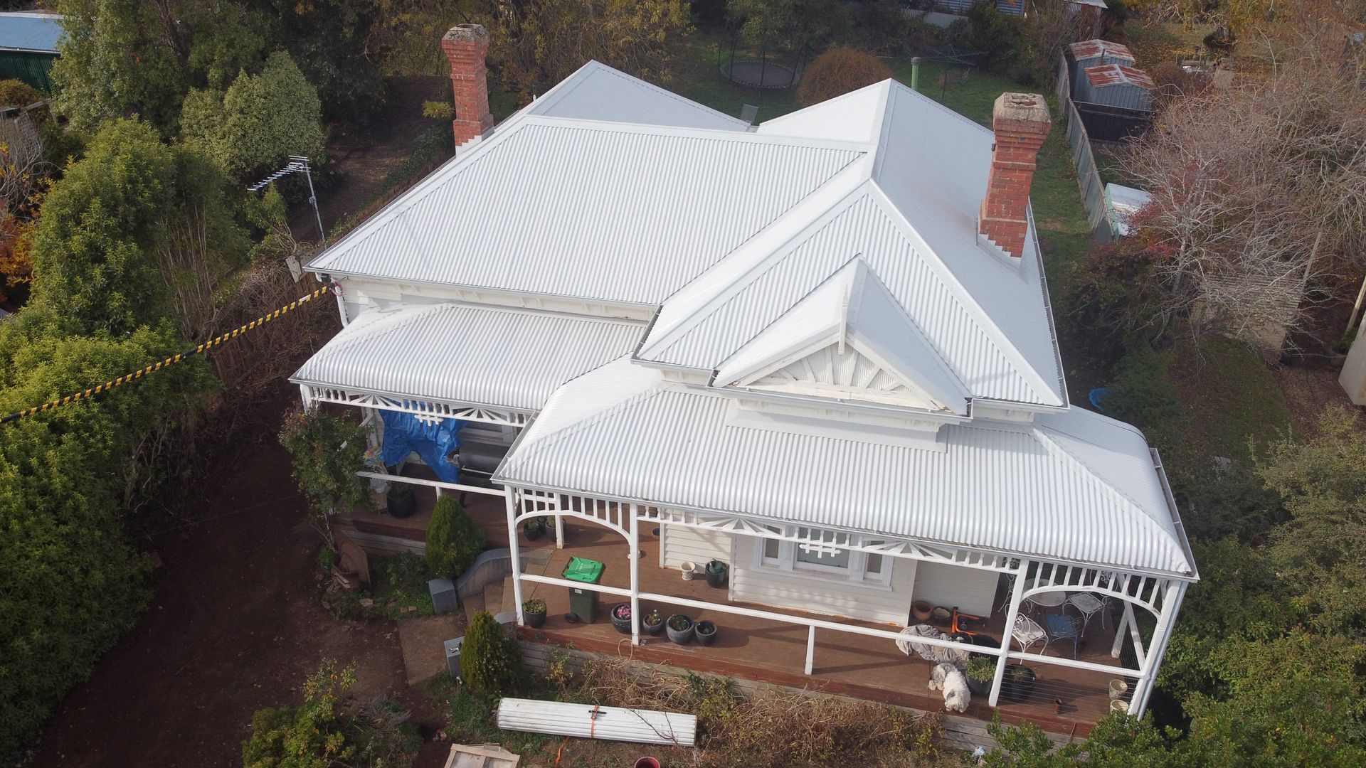 An aerial view of a large white house with a porch surrounded by trees. — iFix Roofing Bendigo in Bendigo, VIC
