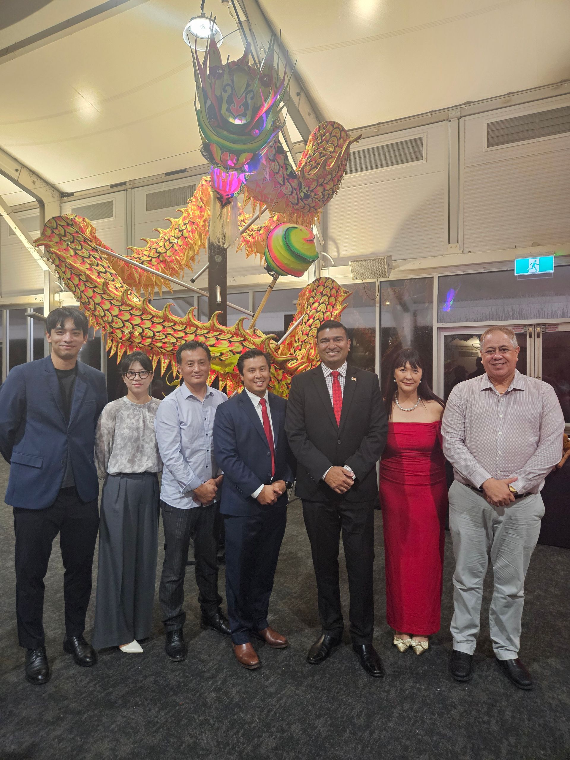 Group of people posing in front of a decorative dragon at an event.