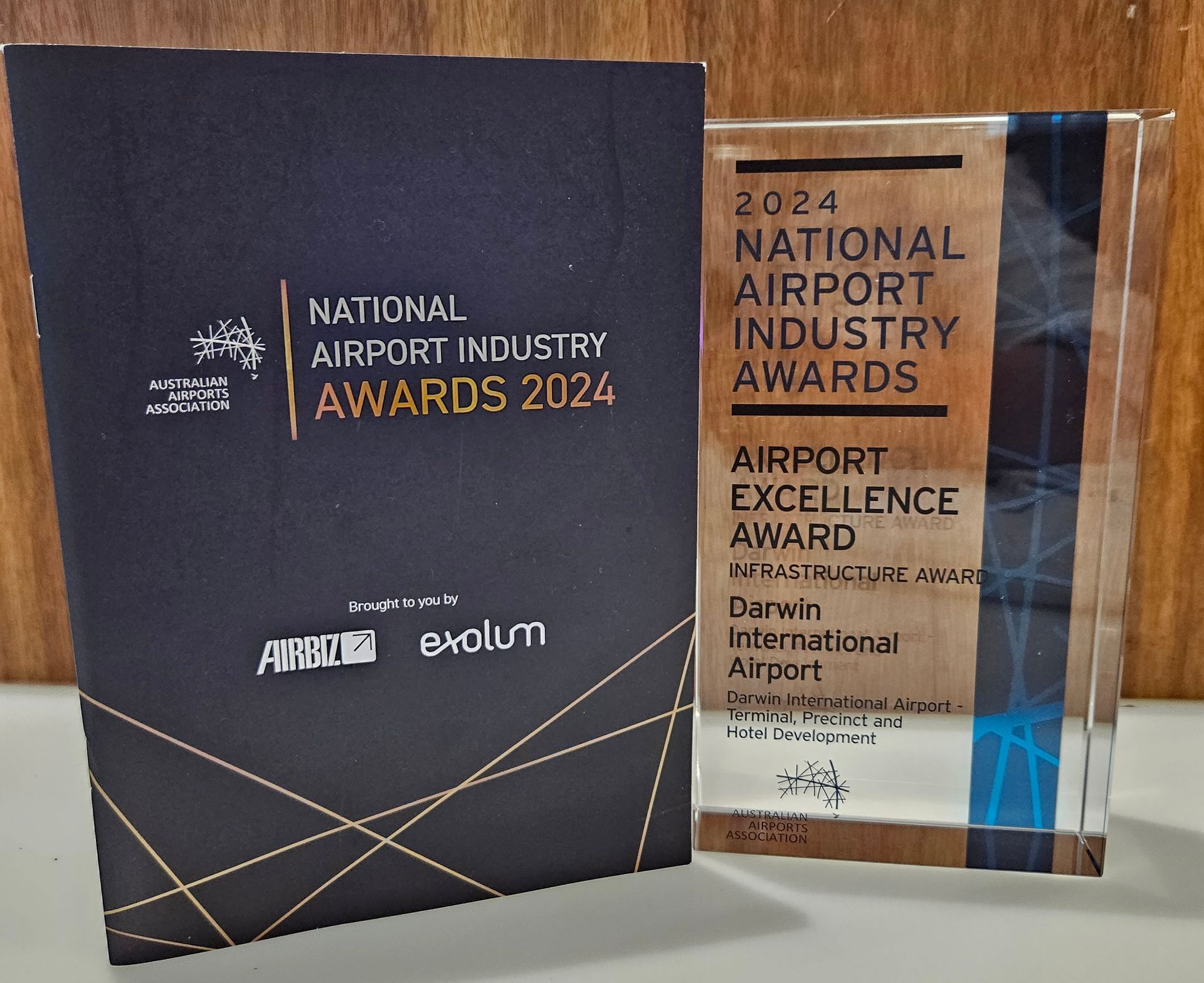 Awards for Darwin International Airport. One is a black book, the other is a clear trophy.