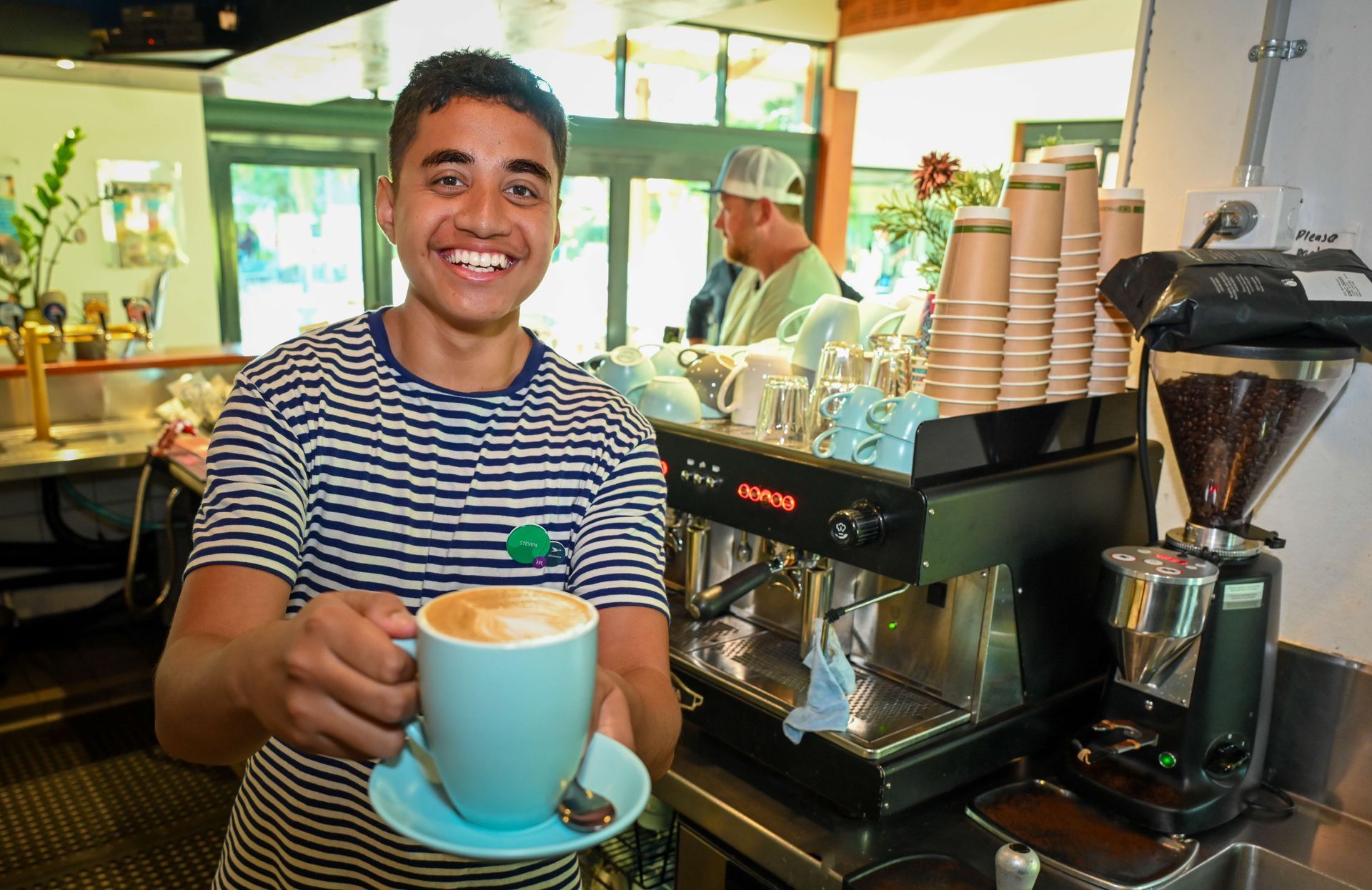 A boy showing his cup of coffee.