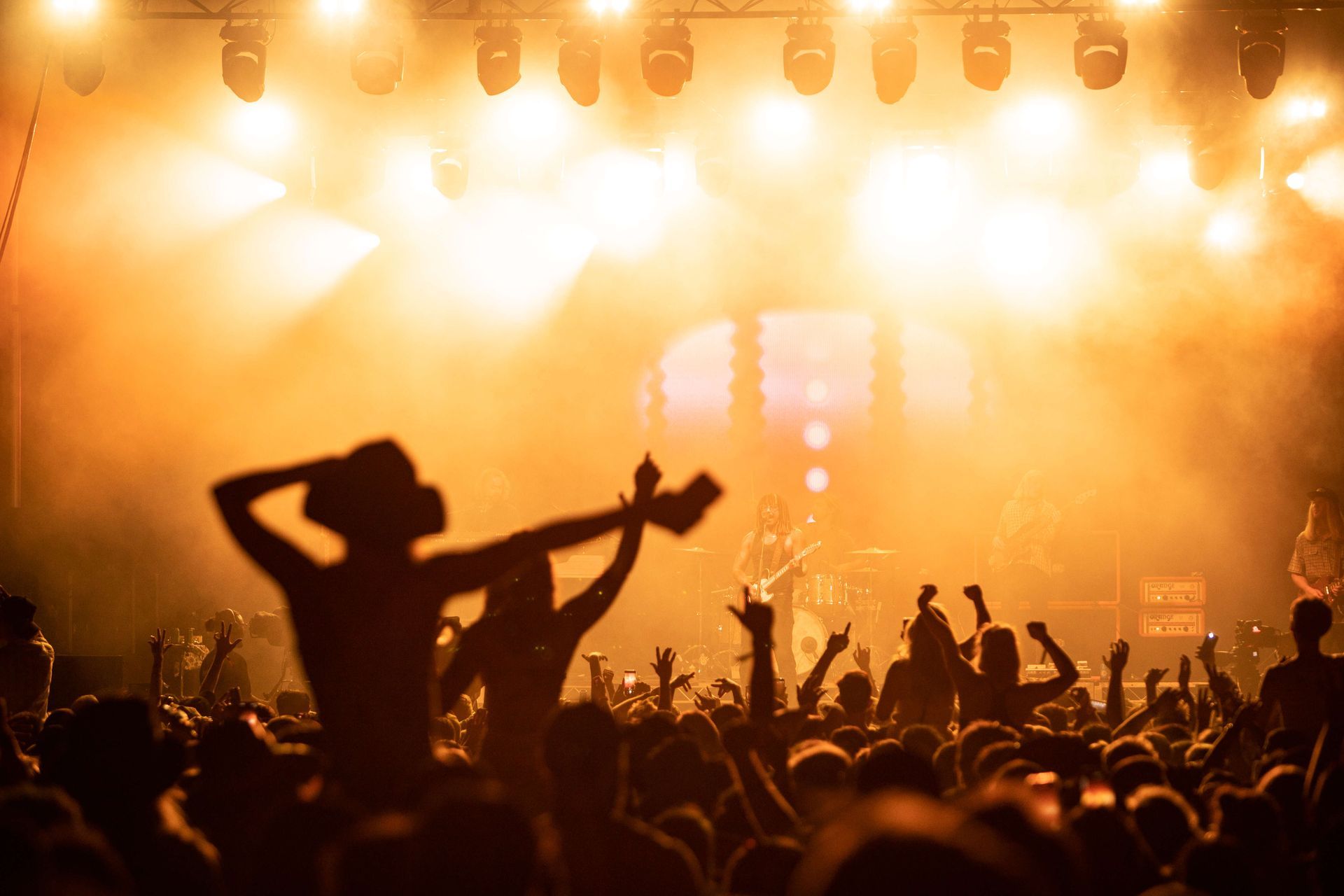 A silhouette of a crowd in front of a concert stage.
\