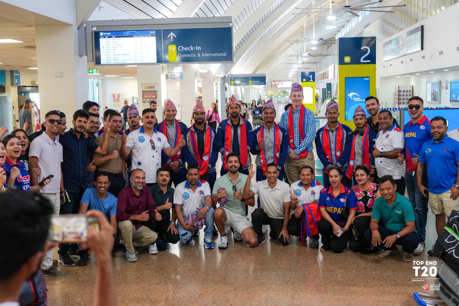 A group of people, some in matching sports jerseys and others in casual clothes, pose for a phot.