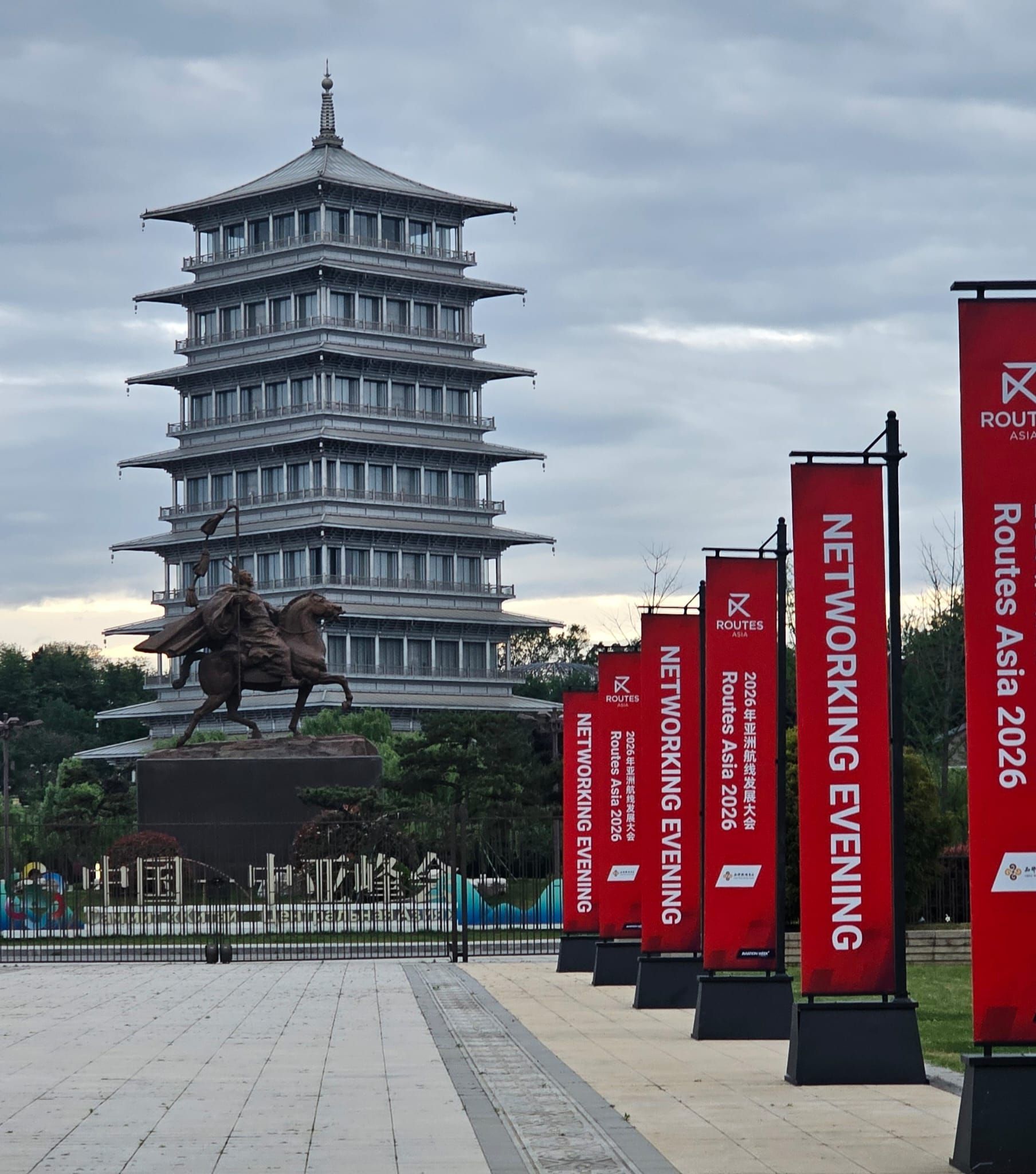 Gray pagoda tower with red event banners along a walkway under a cloudy sky